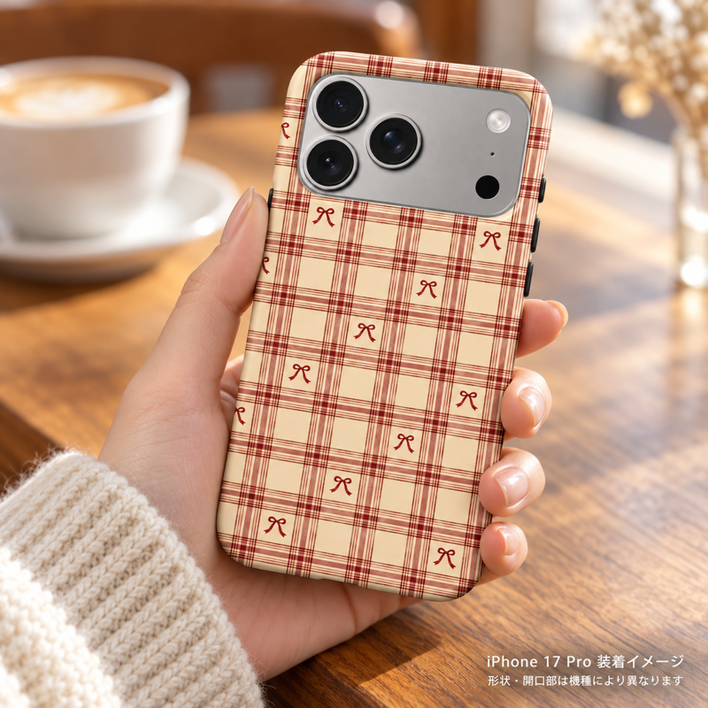 リボンチェック(ブラウンレッド)柄のケースを装着したiPhone 17 Proを手に持つ装着イメージ